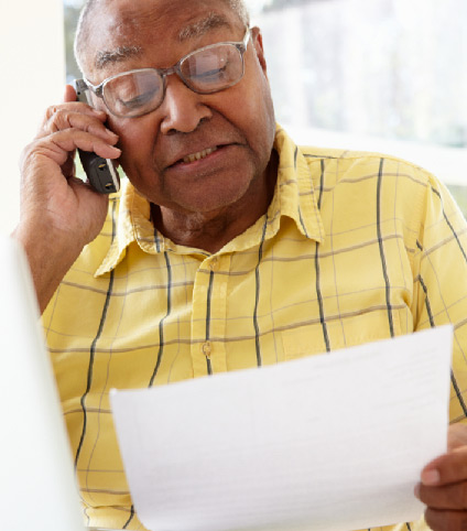 elderly-man-talking-on-the-phone-while-holding-papers elderly man talking on the phone while holding papers