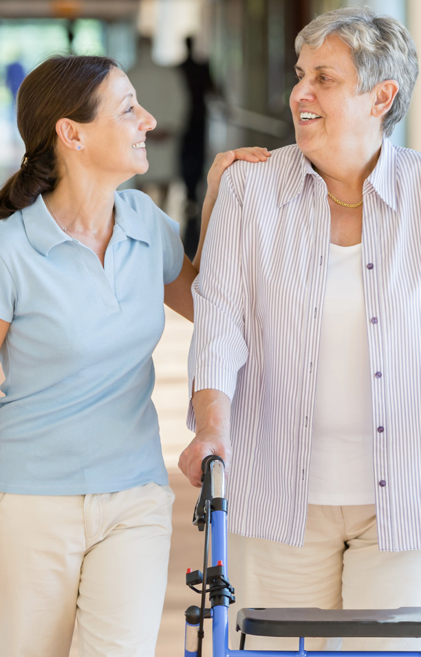 hospital-staff-mamber-holding-the-shoulder-of-a-patient-with-a-walker-as-they-walk-down-the-hall hospital staff mamber holding the shoulder of a patient with a walker as they walk down the hall